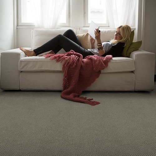 woman relaxing on couch in living room with gray carpet from Carpet Studio & Design Inc. in Los Angeles, CA