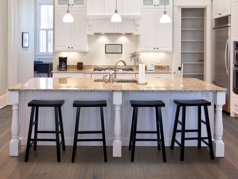 White island table with black chair in kitchen room having a brown hardwood floor from Carpet Studio & Design Inc. in Los Angeles, CA