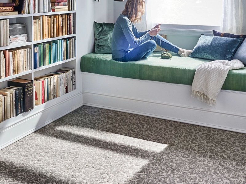 Reading in bed having a beautiful view from window in a bedroom with white furniture and brown carpet from Carpet Studio & Design Inc. in Los Angeles, CA
